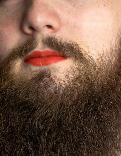 Bärtiger Mann mit rotem Lippenstift auf seinen Lippen, gut aussehend Stolz transgender Porträt lgbtq, transsexuelle Konzept Vollbart Make-up Mund Gesicht Model