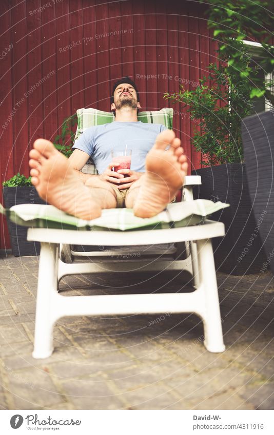 Mann genießt im Sommer einen Cocktail auf der Liege Pause genießen Garten ausruhen liegen Erholung gemütlich Urlaub zu Hause chillen