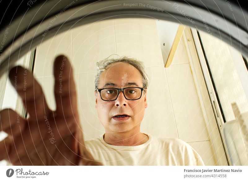 reifer Mann beim Wäschewaschen von innen gesehen in der Waschmaschine Innenansicht Kleidung Wäscherei Bekleidung heimwärts männlich horizontal Arbeit