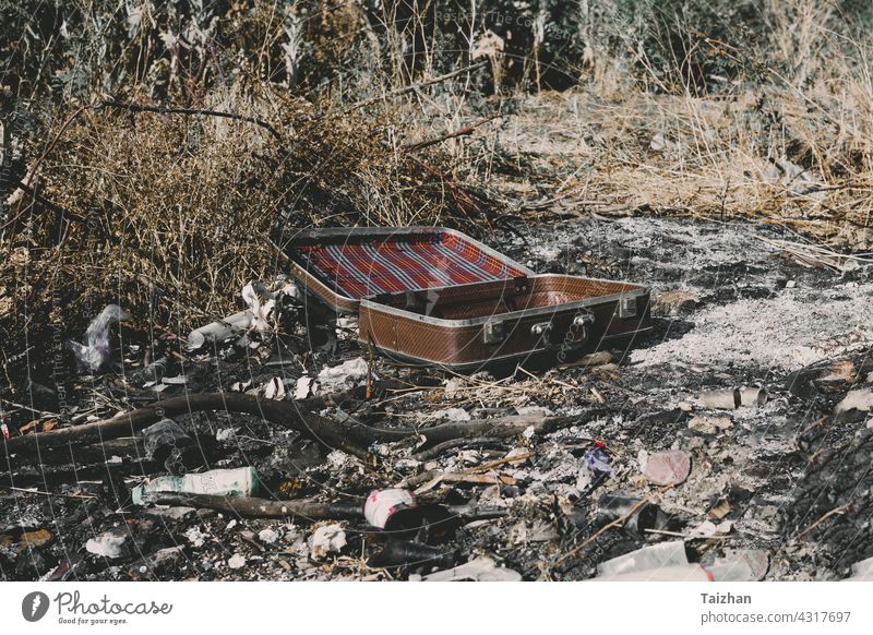Ein alter, verwitterter Vintage-Koffer, der auf der Asche liegt Müll im Freien Konzepte Währung Zerstörung Finanzen Freiheit Ideen Lebensstile keine Menschen