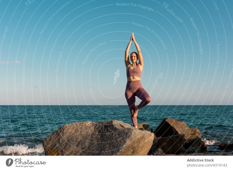 Frau in Baumpose beim Yoga am Meeresufer Baumhaltung üben meditieren Gleichgewicht Strand MEER vrksasana Harmonie Asana Ufer Zen Küste Stein Achtsamkeit Felsen