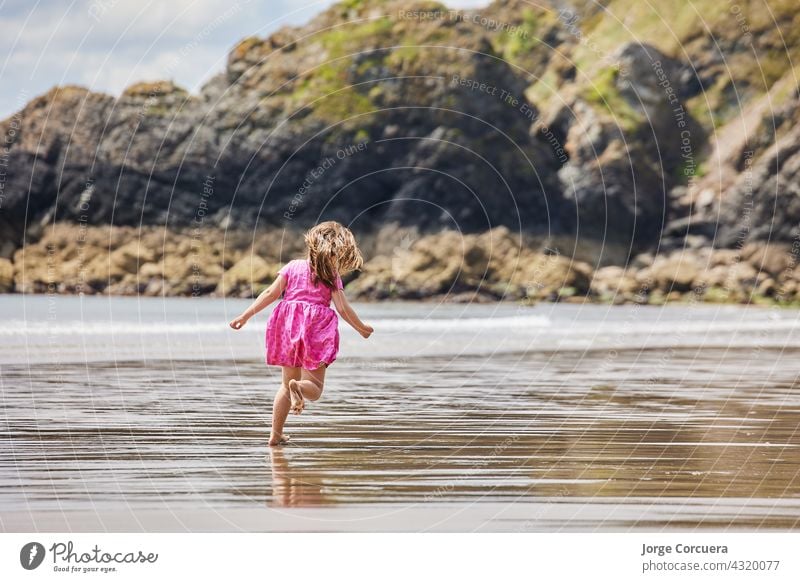 Hispanic Mädchen läuft entlang des Strandes mit großen Felsen im Hintergrund Sand Spielen bezaubernd Kleinkind Kind Sommer jung Kindheit MEER Person niedlich
