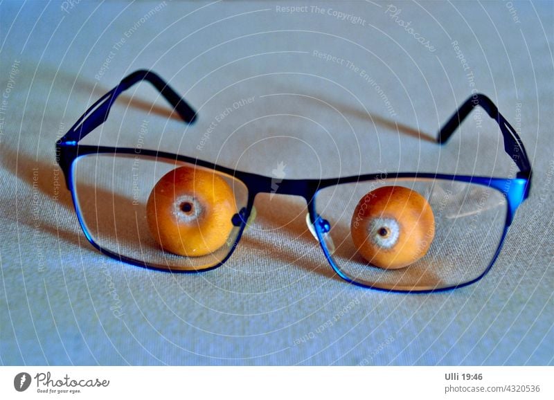 Palmenfrüchtchen mit Lesebrille. Tischdekoration Brille Palmenfrüchte Tischdecke lustige Action lustige Idee Augen blaue Brille orange Pupille Dekoration Scherz