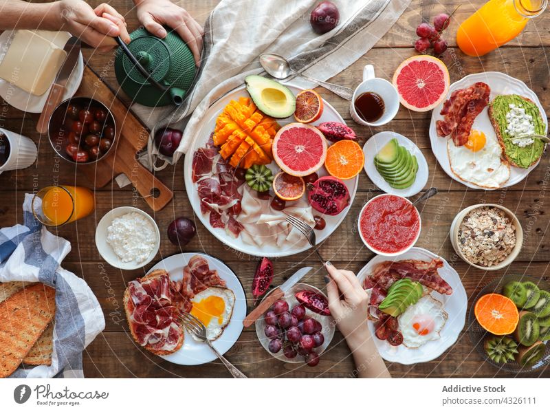 Ansicht des gesunden Frühstücks von oben Hände Servieren Avocado Tomate Spiegeleier Schinken Papaya Granatapfel Kiwi Trauben Speck Brunch Grapefruit Truthahn