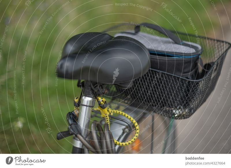 ein auf dem Radweg parkendes Fahrrad mit Blick auf den Sattel und den Fahrradkorb, in dem sich eine Kameratasche befindet Fahrradtour Fotosafari