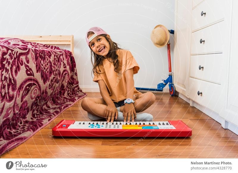 Glückliche hispanische Mädchen trägt eine rosa Tasse spielen in einem roten Klavier in ihrem Schlafzimmer Pianist Person Akkord Klassik Finger Rhythmus kreieren