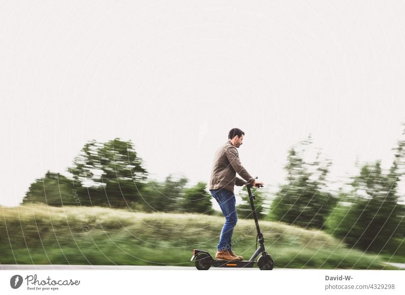 Mann unterwegs mit dem E-Roller fahren eroller Natur Straße Mobile nachhaltig modern Geschwindigkeit elektrisch Elektroroller