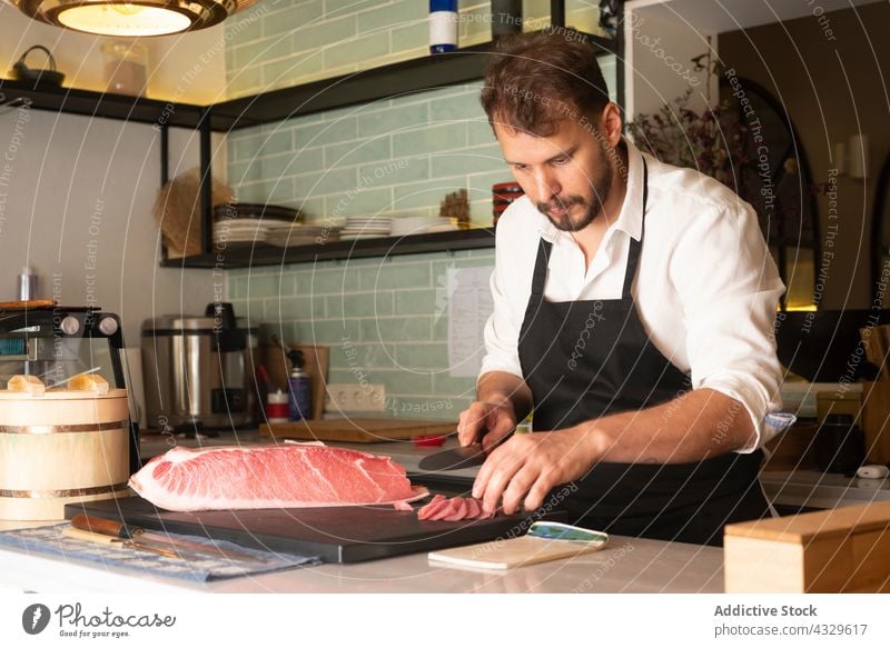 Männlicher Koch schneidet Fisch in der Küche eines Restaurants Küchenchef Sushi Meeresfrüchte Mann geschnitten Orientalisch frisch männlich Lebensmittel