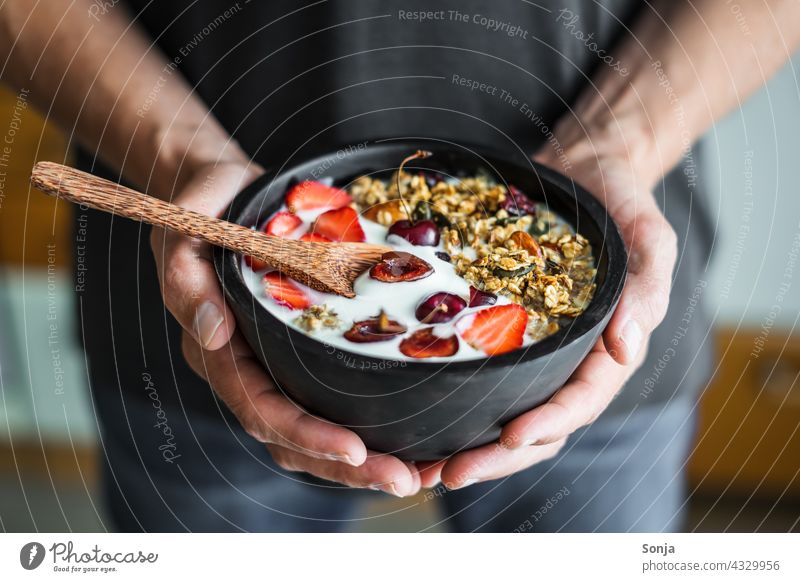 Mann hält eine Schüssel mit Granola, Joghurt und Erdbeeren in den Händen Frühstück halten teilabschnitt Müsli Gesundheit geröstet Nuss Vintage Holz Diät Löffel