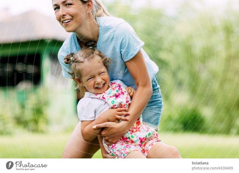 Eine junge Mutter und ihr süßes kleines Mädchen haben Spaß in einem sonnigen Garten. Das Konzept einer glücklichen Kindheit und Mutterschaft Baby Glück Mama