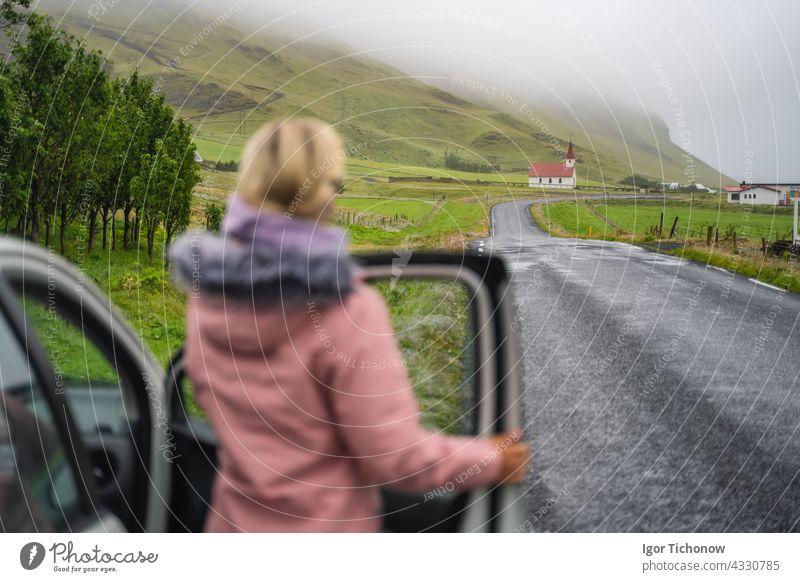Frau genießt typisch ländliche isländische Kirche mit rotem Dach aus dem Mietwagen in der Region Vik. Island horizontal Miete Landschaft Kapelle Europa reisen