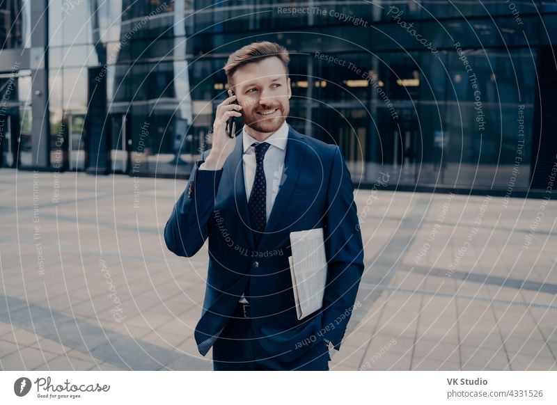 Glückliche Büroangestellte mit Zeitung im Gespräch auf Smartphone gutaussehend Geschäftsmann Telefon Mobile Anruf Lächeln männlich Nachrichten blau