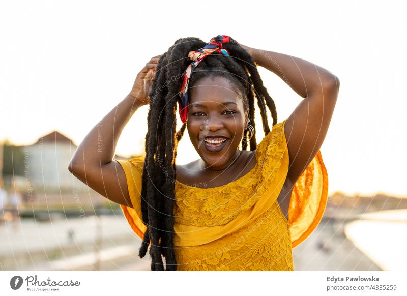 Schöne junge Frau genießt die Natur bei Sonnenuntergang Rastalocken stolz echte Menschen Stadtleben Afroamerikaner Afrikanisch schwarz Ethnizität sonnig