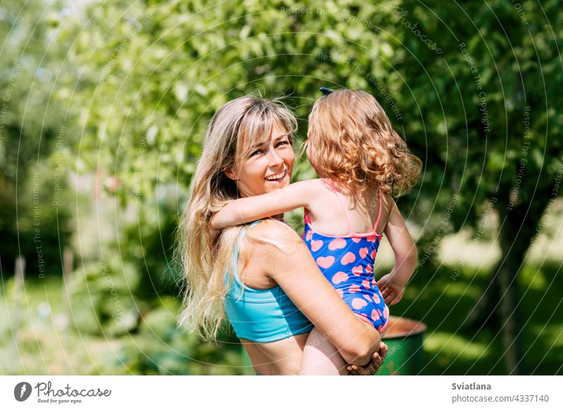 Eine junge Mutter hält ihre kleine Tochter in den Armen an einem Sommertag im Garten oder Park wenig Familie Eltern Mama Kind Kindheit Glück