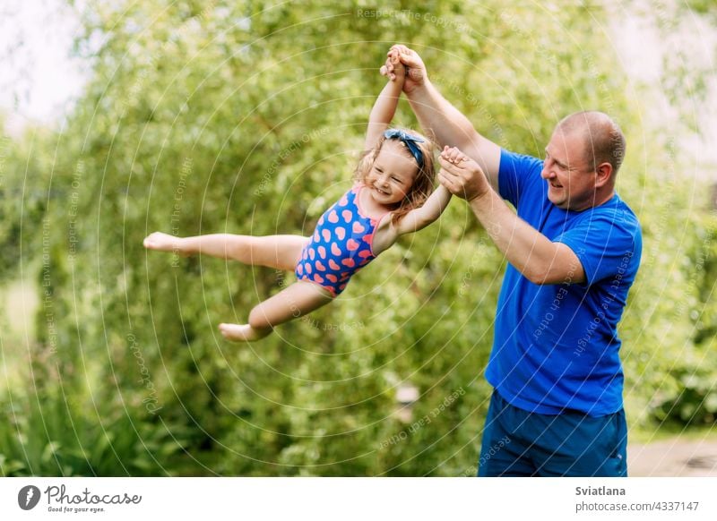 Ein niedlicher Vater und ein kleines Mädchen spielen zusammen. Das Kind nimmt in den Händen seines Vaters ab Baby Zusammensein fliegen Spielen Tochter Mann Park