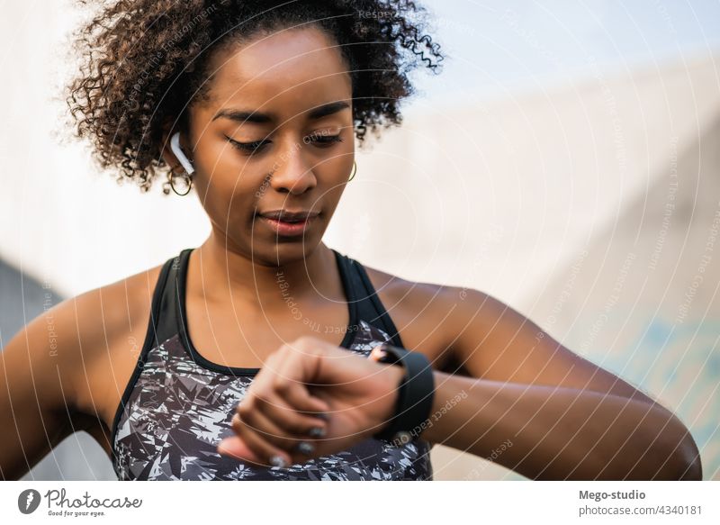 Fitness-Frau, die die Zeit auf einer Smartwatch überprüft. Afro-Look Übung Überprüfung smartwatch trainiert. Sport Sportler Gerät aktiv Körper Motivation Herz