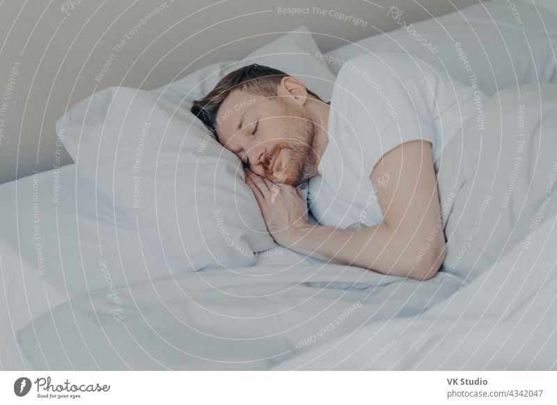 Hübscher junger Mann schläft bequem im Bett zu Hause schlafen Mittagsschlaf Glück gutaussehend Schlafzimmer gemütlich Streu sich[Akk] entspannen friedlich