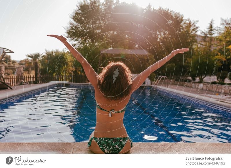 Rückenansicht der kaukasischen Frau sitzt am Pool Seite tragen Bikini-Badebekleidung. Sommerzeit, Urlaub und Lebensstil Kaukasier Schwimmbad Sonnenbrille heiß