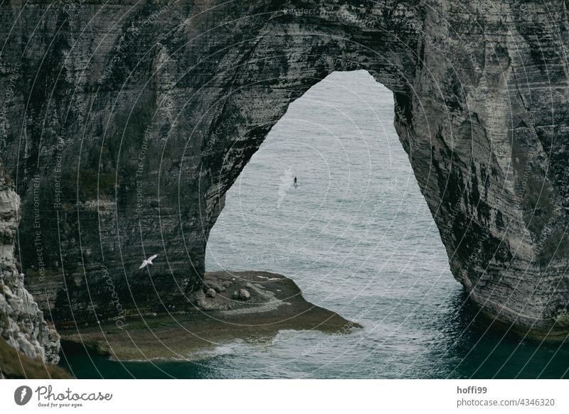 Der Bogen im Meer mit Standuppaddler bei  Etretat. felsenbrücke natürliche Bögen Felsküste Étretat Standuppaddling