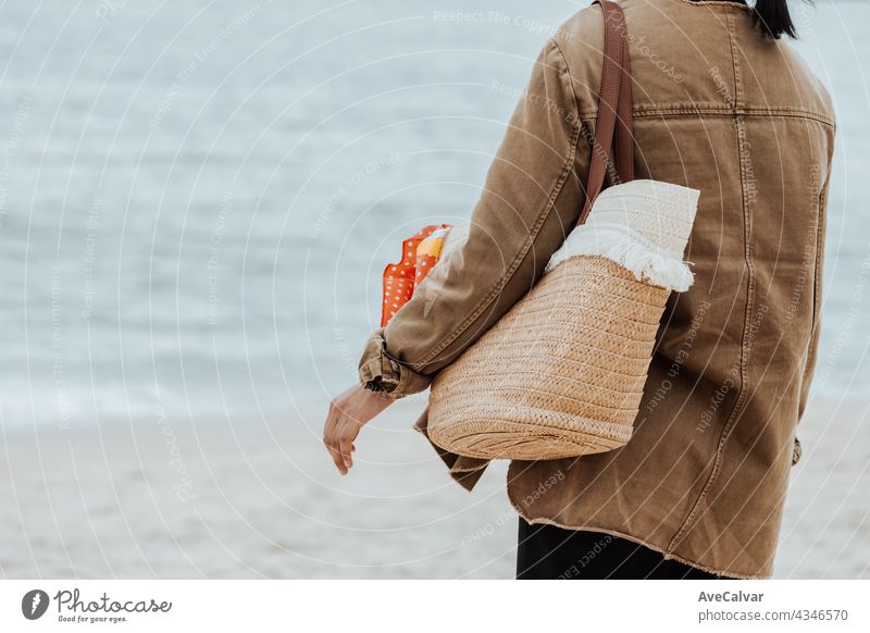 Nahaufnahme einer Frau am Strand hält eine Strandtasche während eines hellen Tages, kopieren Raum, Urlaub und Freiheit Konzept Person Tasche Rückseite lang