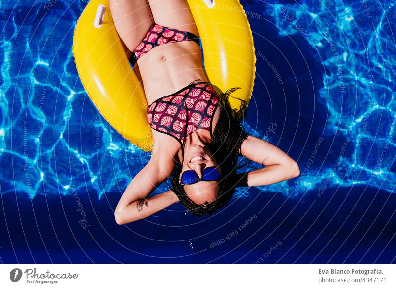 Draufsicht auf glückliche kaukasische Frau schwimmt auf gelben Donuts aufblasbare am Swimmingpool. Sommerzeit, Urlaub und Lebensstil Kaukasier fliegend