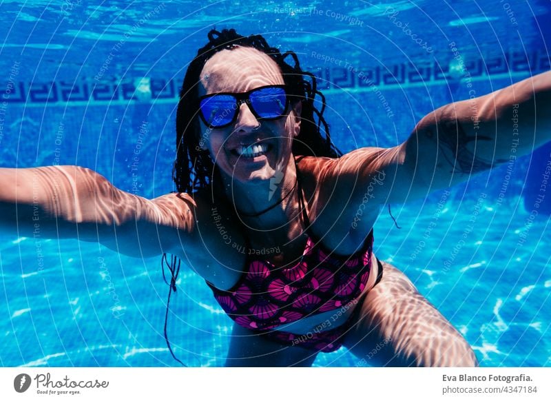 glückliche kaukasische Frau mit Sonnenbrille Tauchen im Schwimmbad. Unterwasser-Ansicht. Sommerzeit und Urlaub Konzept unter Wasser Spaß Liebe Blauwasser