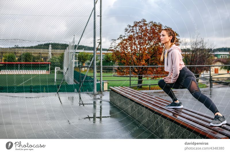 Junge Sportlerin streckt die Beine im Freien strecken auf einer Bank selbstbewußt Frau Athlet Textfreiraum Körper Aufwärmen Training geduckt trainiert.