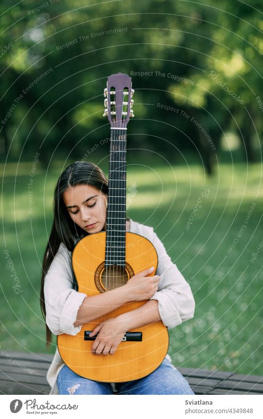 Ein attraktives Mädchen mit einer Gitarre im Park. Das Konzept der kreativen Hobbys und Profis. Das Mädchen ist ein Musiker Porträt Gitarrenspieler Lifestyle
