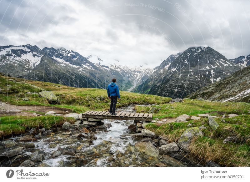 Wanderer rastet auf einer kleinen Brücke über einen Gebirgsfluss am Schlegeis See, Zillertaler Alpen, Österreich schlegeis stausee schön wandern tirol reisen
