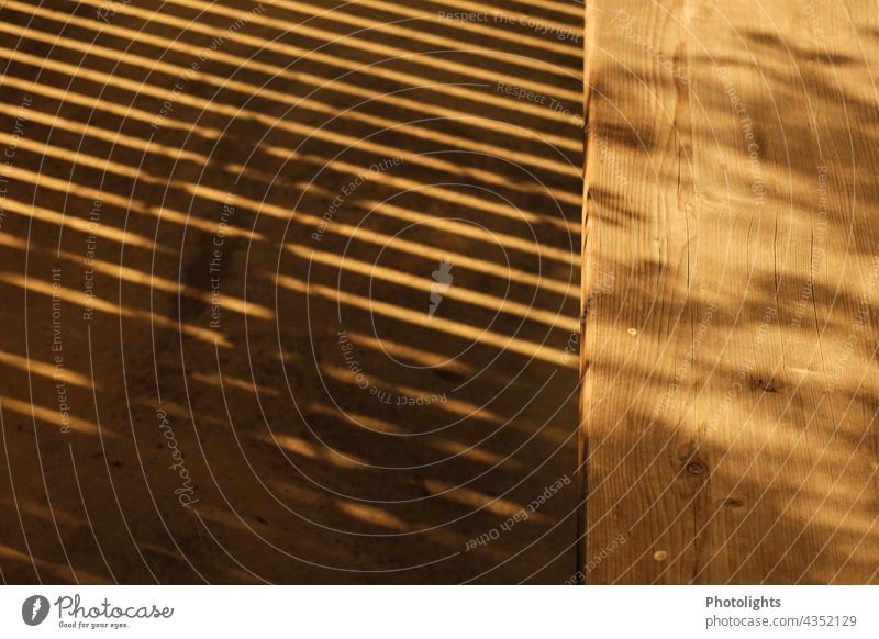 Schatten eines Gitters vor Holzbank Holzbrett Wärme Licht Sonne Sonnenlicht Kontrastreich Schattenspiel Farbfoto Außenaufnahme Menschenleer Tag Gedeckte Farben