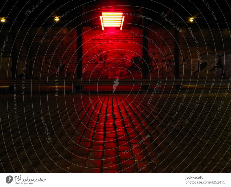 Dunkler Tunnel durch rotes Neonlicht beleuchtet Verkehrswege Straße Wand dunkel leuchten Lichtinstallation Beleuchtung Kopfsteinpflaster Säule Straßenkunst