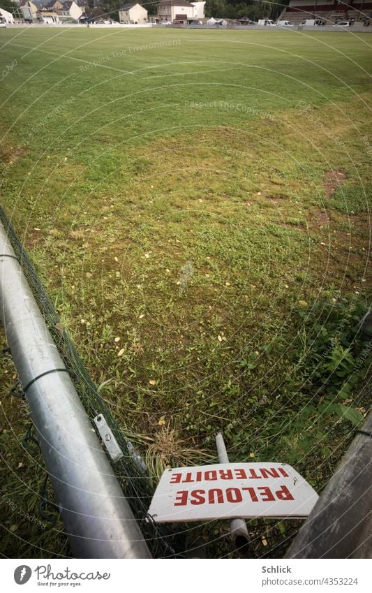 Schild mit roter Aufschrift PELOUSE INTERDITE Rasen betreten verboten steht in der Ecke eines Fußballplatzes französisch Frankreich Schrift Rasenplatz Winkel