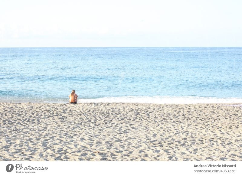 Frau, die allein am Strand sitzt und das Meer betrachtet, mit Platz für Ihren Text horizontal Farbbild Menschen Kaukasier im Freien MEER Seeküste Sommer