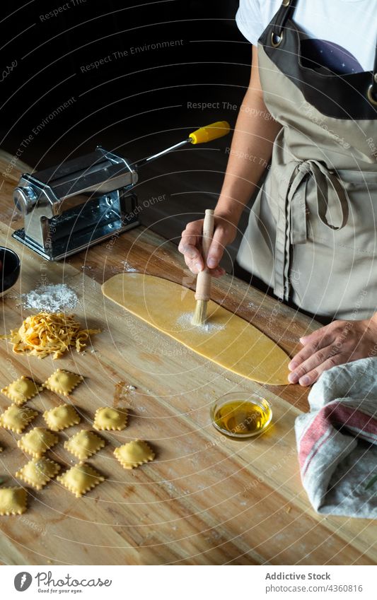 Anonyme Person bei der Zubereitung von hausgemachten Raviolis Küchenchef Lebensmittel Vorbereitung Essen zubereiten Tisch hölzern Mehl Holzplatte Teigwaren