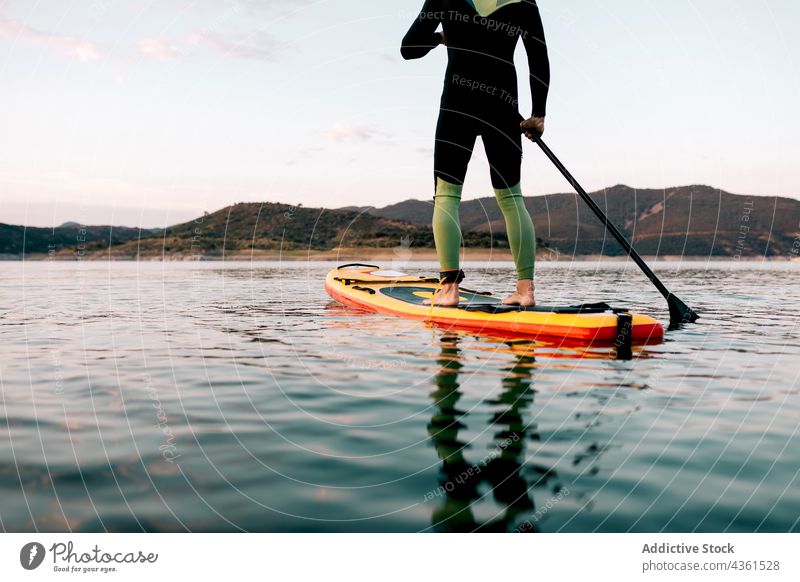Unbekannter Mann schwimmt auf Paddleboard im Meer Surfer Paddelbrett Zusatzplatine Schwimmer MEER Sonnenuntergang Sommer Holzplatte männlich Wasser Aktivität
