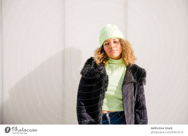 Afro-Frau, die an einer Mauer auf der Straße steht Person Afro-Look modisch jung Erwachsener Stehen krause Haare Porträt urban Mode Mädchen im Freien Großstadt