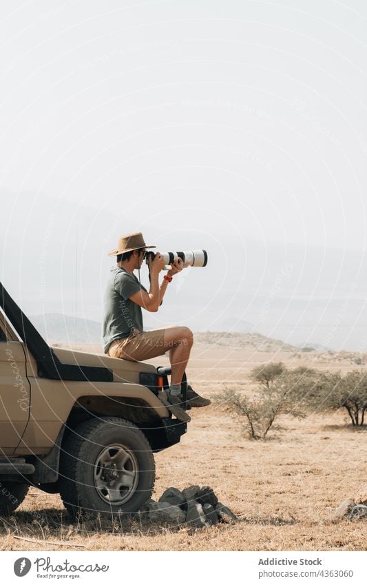 Reisender Fotograf macht Fotos während einer Safari reisen Mann fotografieren Fotoapparat Fotografie Telebild Linse männlich Offroad Geländewagen PKW Abenteuer