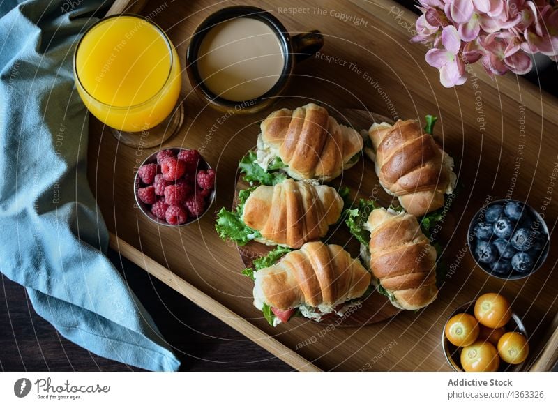 Appetitliches französisches Frühstück mit Croissant-Sandwiches auf dem Tablett Belegtes Brot Lebensmittel Saft Kaffee geschmackvoll dienen Tisch lecker frisch