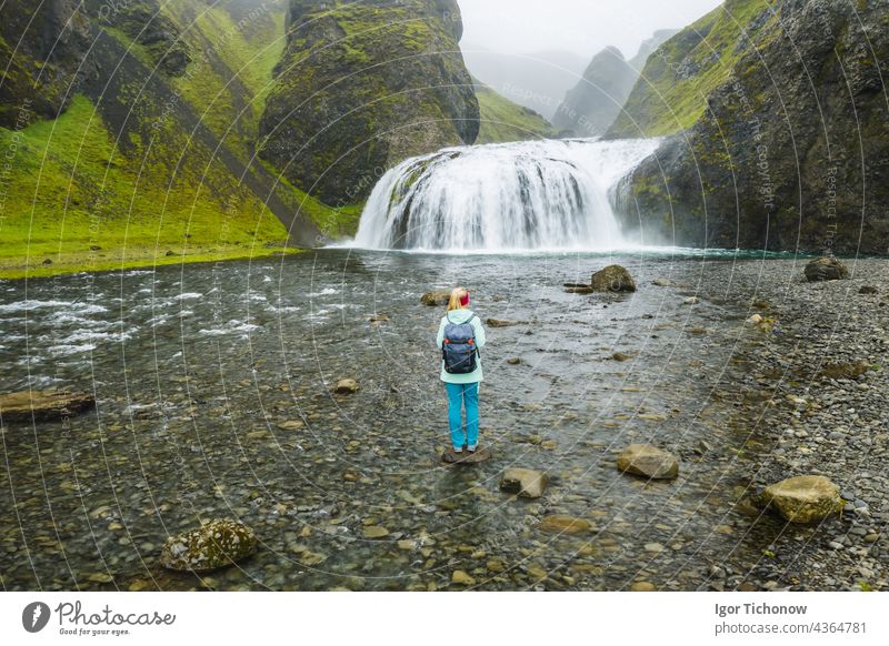 Luftaufnahme einer Wanderin mit Rucksack vor dem Stjornarfoss-Wasserfall in Südisland Island Frau stjornarfoss Antenne isländisch Fluss Natur reisen Felsen