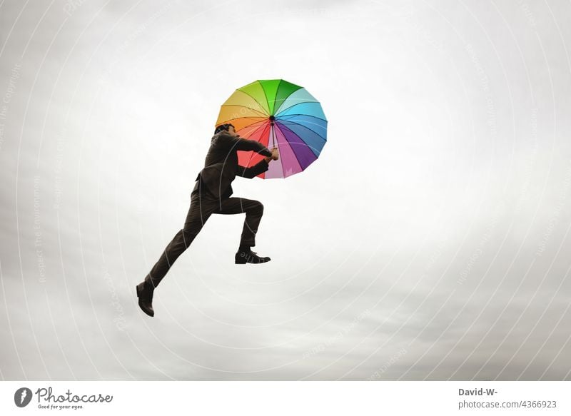 Mann fliegt mit dem Regenschirm Freiheit fliegen schweben Schwerelosigkeit bunt Himmel aufsteigen Leichtigkeit Business Anzugträger Erfolg konzept