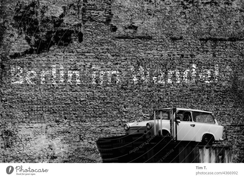 ein alter Hof mit Trabant Auto und einem Graffiti " Berlin im Wandel " s/w trabant Stadt Menschenleer Außenaufnahme Stadtzentrum Hauptstadt Schwarzweißfoto Tag