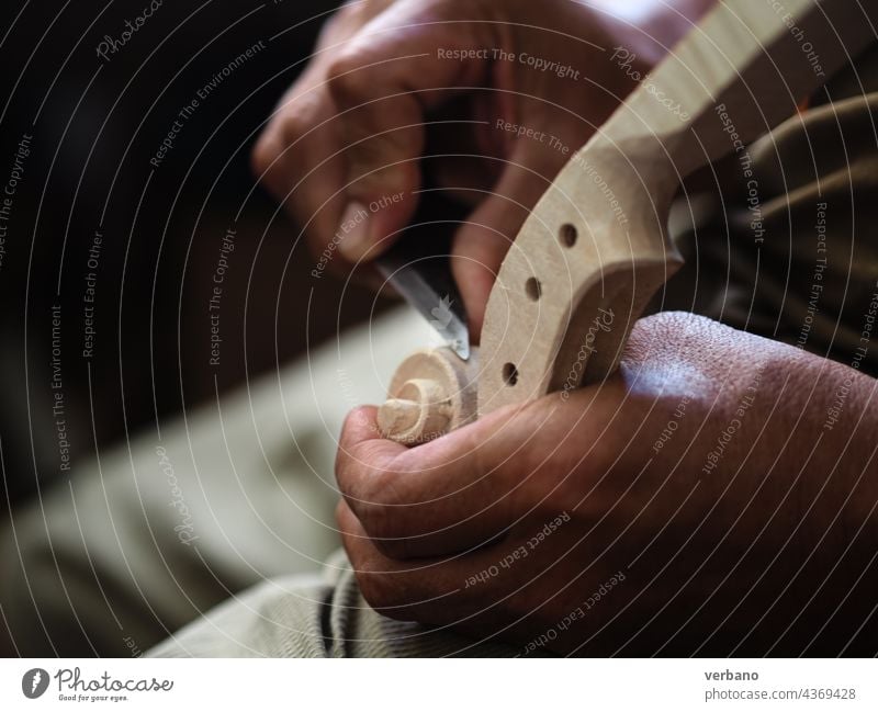 Geigenbauermeister mit einem Messer beim Schnitzen eines Geigenkopfes und einer Schnecke des Modells Stradivarius Zupfinstrumentenmacher Bratsche Herstellerin