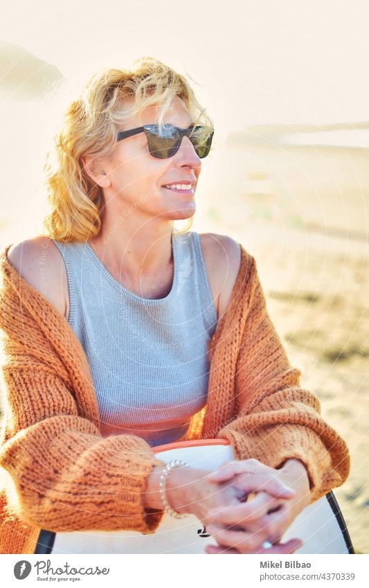 Porträt einer jungen reifen blonden kaukasischen Frau im Freien in einem Strand mit einem Bodyboard und Sonnenbrille in einem sonnigen Tag. Lifestyle Wellness