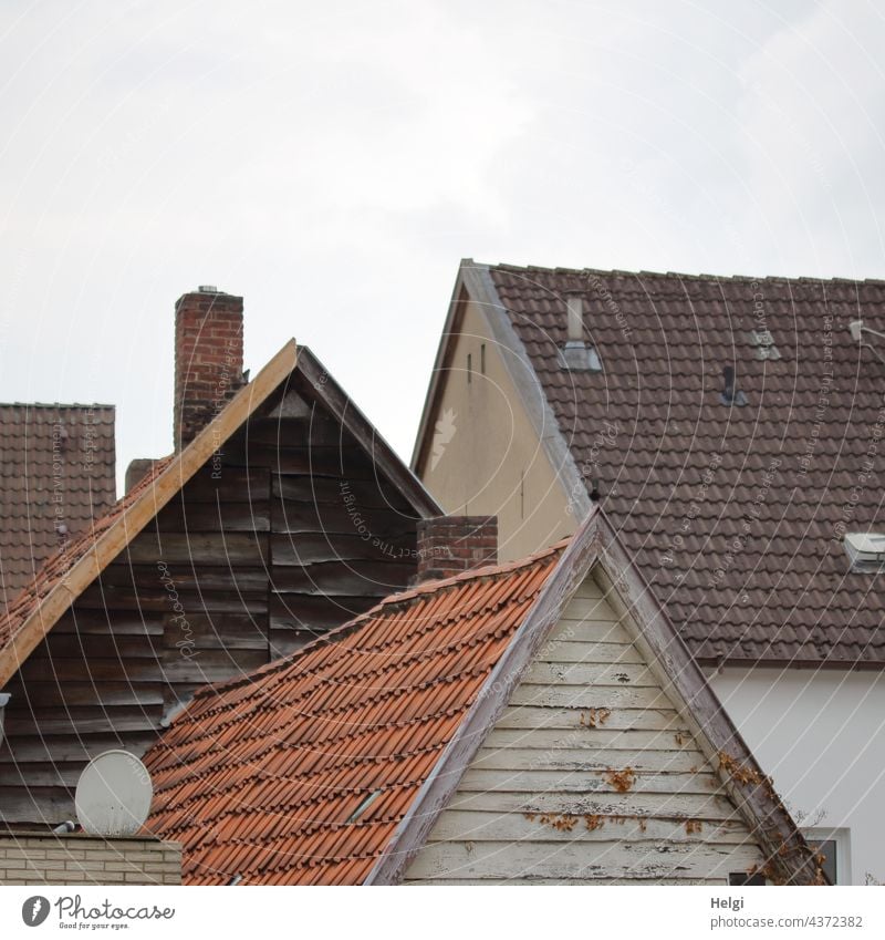 Zwischenräume - mehrere unterschiedliche Hausgiebel und Dächer vor blaugrauem Himmel Gebäude Architektur Giebel Dach Dachpfannen Holzverkleidung Schornstein