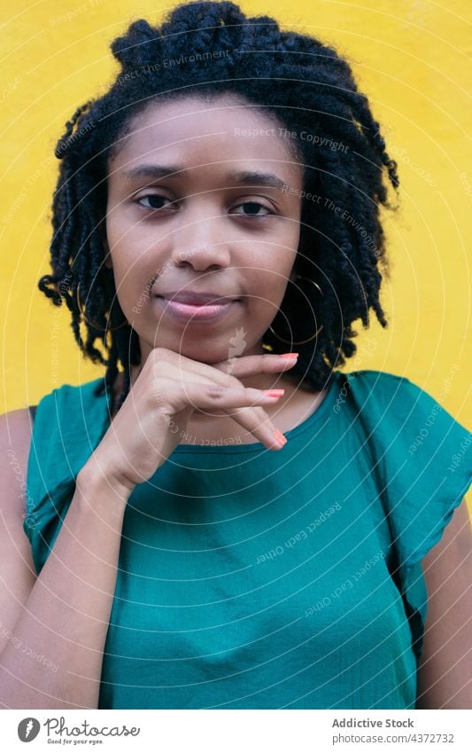 Porträt einer jungen Frau mit Afrofrisur, die an einer Wand lehnt Afrikanisch Menschen Glück Amerikaner Model Dame Ethnizität Afro-Look Lachen Behaarung Straße