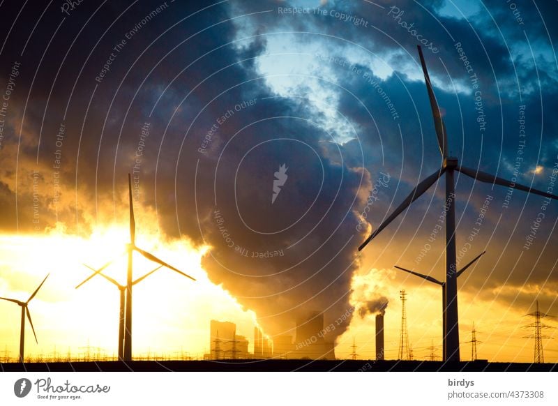 Windräder vor einem Braunkohlenkraftwerk bei Sonnenuntergang im Gegenlicht. Windkraftanlagen CO2-Ausstoß Klimawandel Luftverschmutzung Rauch Emission