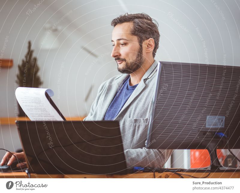 Ein Mann im Raum studiert die Dokumente. Ein Mann in Freizeitkleidung an einem Laptop. Aus der Ferne arbeiten Business Computer Schriftstück Geschäftsmann