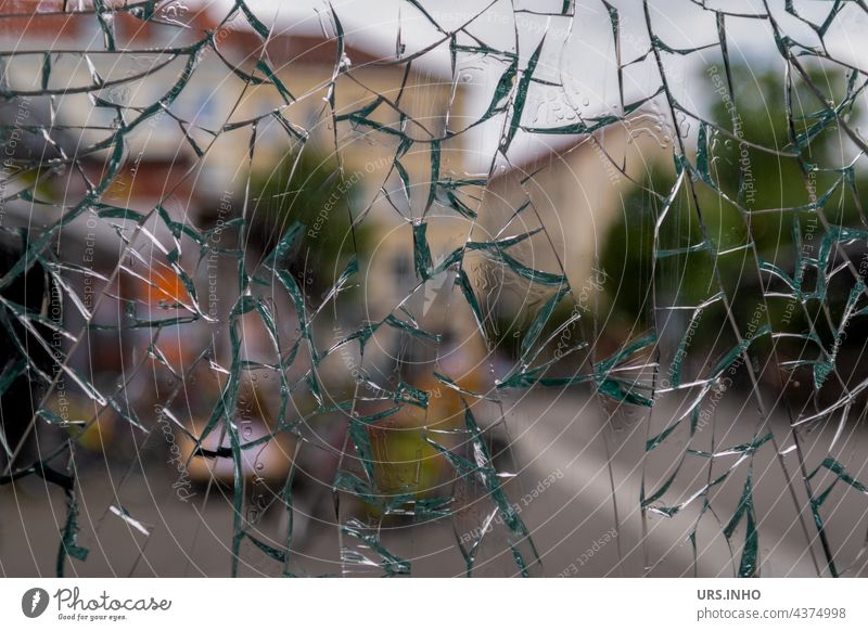 durch die stark zersplitterte Fensterscheibe aus Glas kann man im Hintergrund die Häuser noch erkennen Scheibe Glasscheibe durchsichtig Außenaufnahme glas