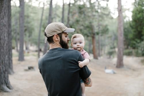 Vater trägt seine kleine Tochter auf einem Spaziergang durch den Wald 25-30 30-35 30-40 Baby Vollbart Bonden Kalifornien Lager Wohnmobil Camping Campingplatz