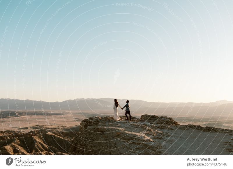 Mann und Frau halten sich an einem Aussichtspunkt in der Wüste an den Händen anza-borrego-wüste Ödland Kakteen Kaktus Paar kostümiert Erosion Schriftarten Punkt